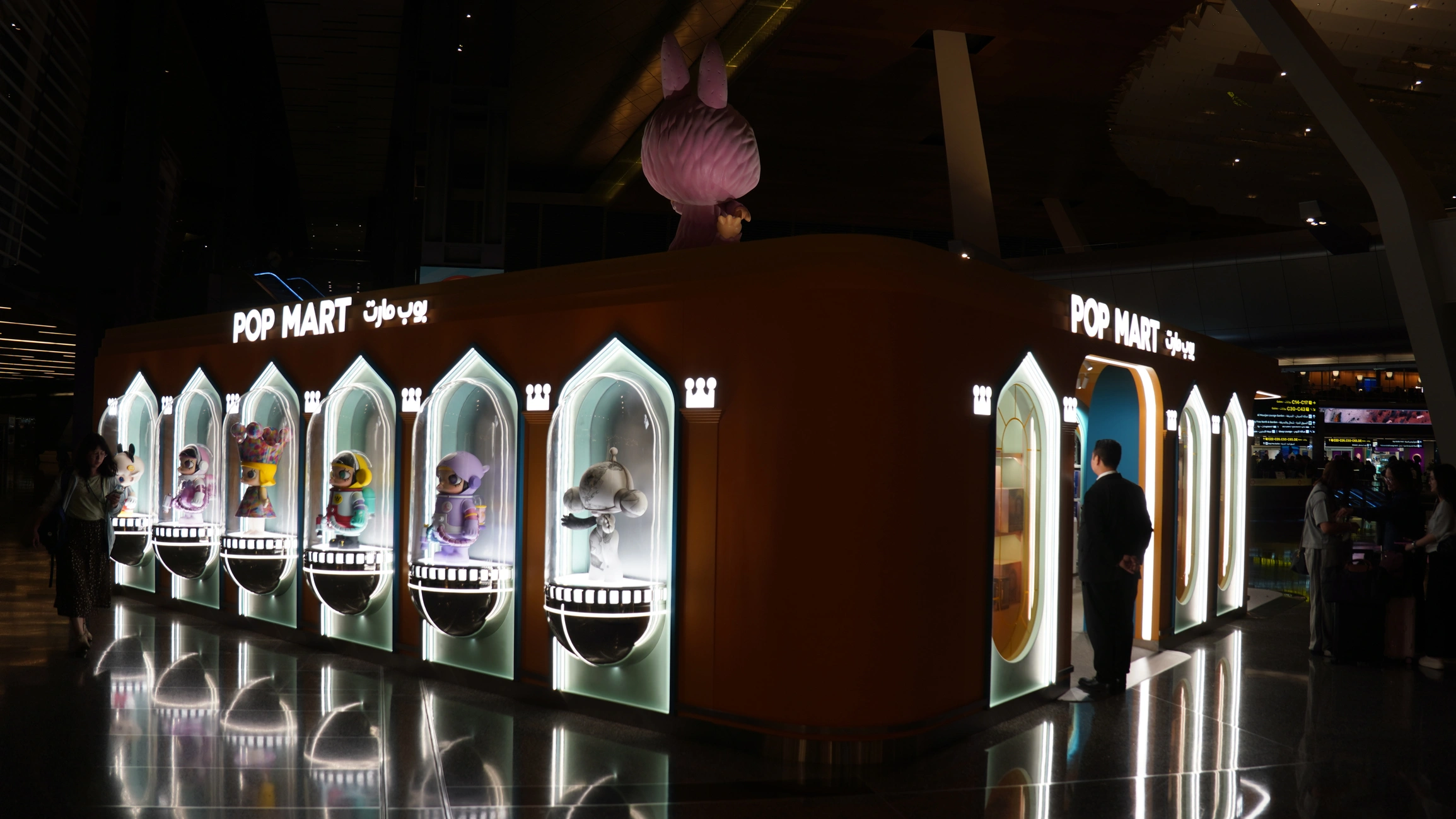 Bright orange Pop Mart retail installation with illuminated arched display windows showing collectible figurines