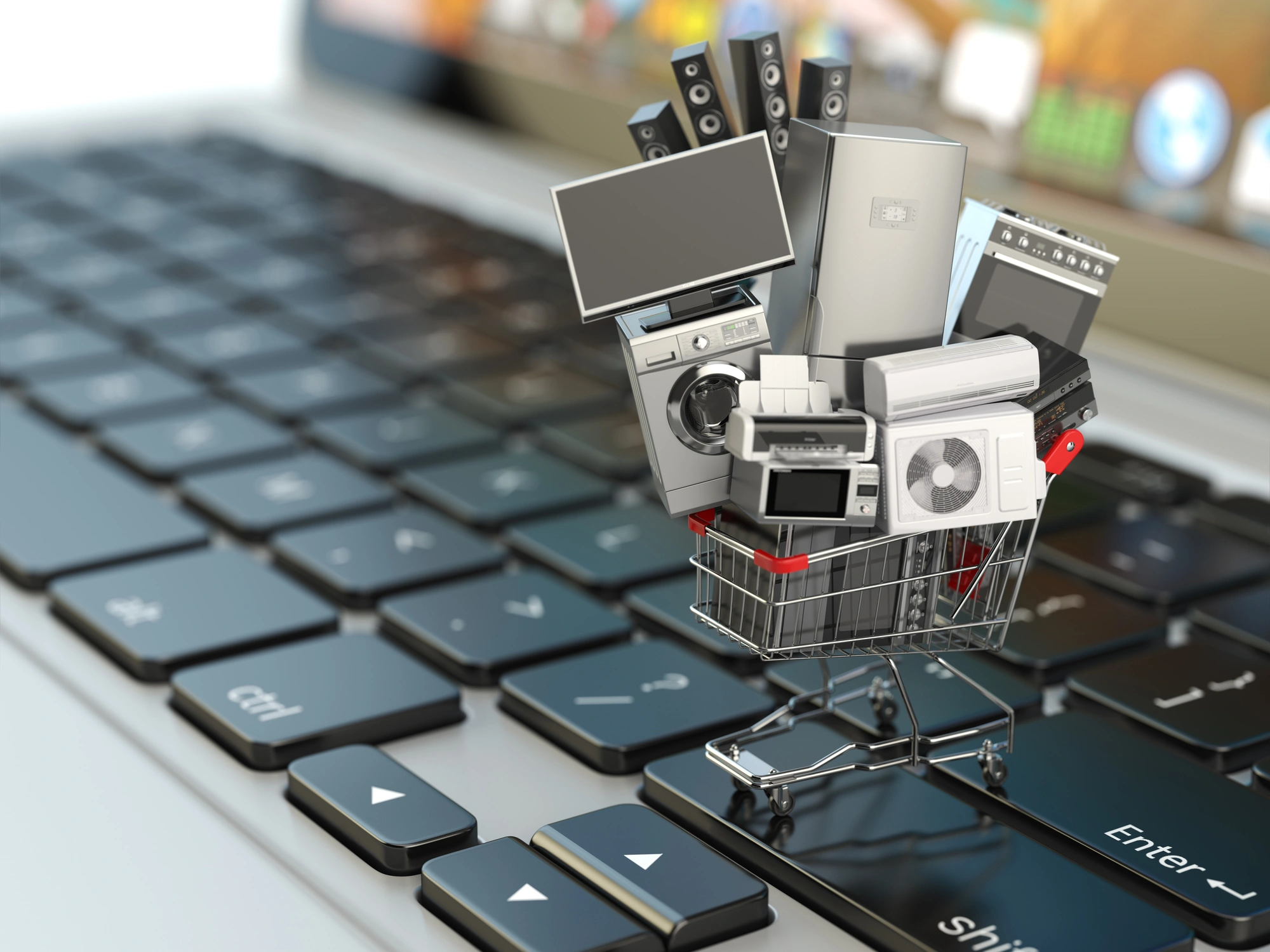 Miniature shopping cart filled with home electronics on a computer keyboard